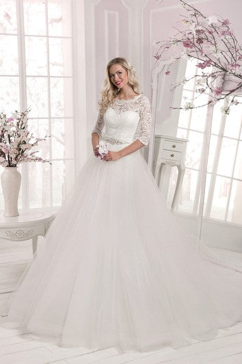 Robe trapèze à encolure festonnée, manches longues, haut en tulle et dentelle, détails en cristal et longue traîne